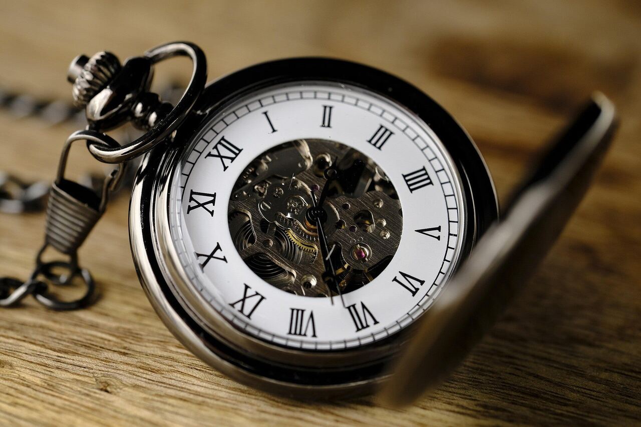 An open pocket watch lying on a wooden table